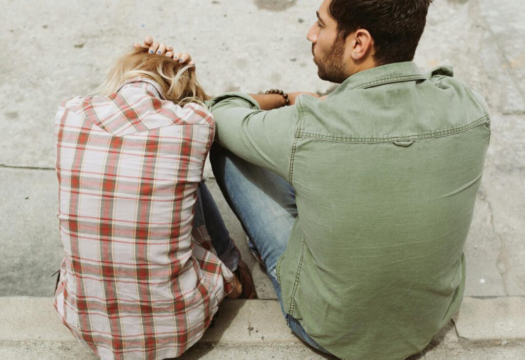 A thoughtful couple sitting quietly on a couch, symbolizing emotional distance and reflection in a relationship.